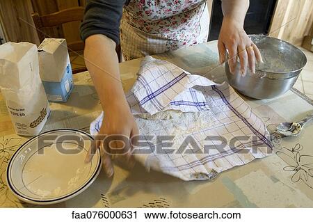 Stock Image - Woman covering pastry dough with towel, cropped. Fotosearch