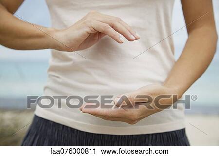 Stock Image - Woman doing "hold the ball" tai chi chuan move, mid section. Fotosearch