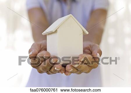 Stock Image - Woman holding small model house, cropped. Fotosearch