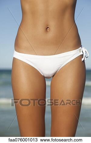 Stock Image - Woman in bikini bottom, mid section. Fotosearch
