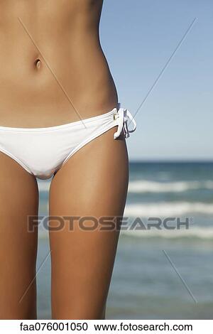 Stock Image - Woman in bikini bottom, mid section. Fotosearch