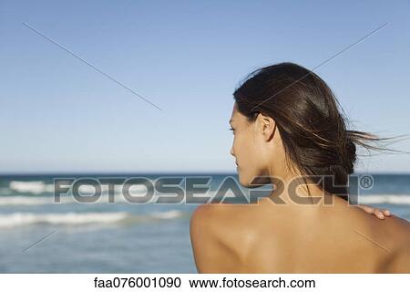Stock Image - Woman looking at ocean, rear view. Fotosearch