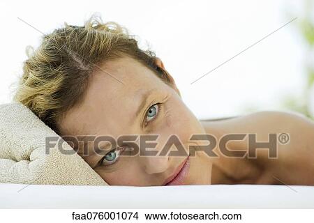 Woman lying down with head resting on towel, portrait View Large Photo Image Picture - Woman lying down with head resting on towel, portrait. Fotosearch