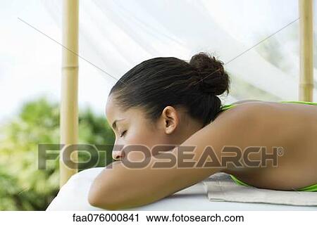 Stock Image - Woman lying down with head resting on arms. Fotosearch
