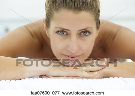 Stock Photo - Woman lying down with head resting on arms, portrait. Fotosearch