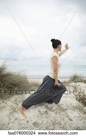 Picture - Woman practicing tai chi chuan on beach, side view. Fotosearch