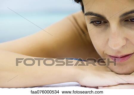 Picture - Woman resting head on arms, looking away in thought. Fotosearch