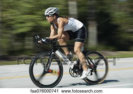 Stock Image - Woman riding road bike, blurred motion. Fotosearch