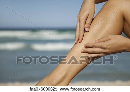 Stock Photography - Woman rubbing leg, low section. Fotosearch