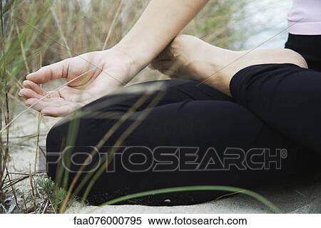 Stock Photography - Woman sitting in lotus position, fingers in meditation position, cropped. Fotosearch