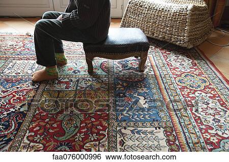Woman sitting on ottoman in living room, low section View Large Photo Image Stock Photograph - Woman sitting on ottoman in living room, low section. Fotosearch