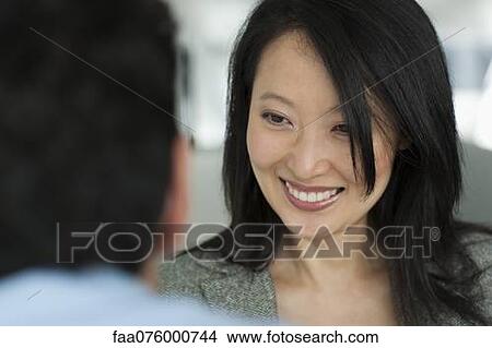Woman smiling cheerfully at man in foreground, cropped View Large Photo Image Picture - Woman smiling cheerfully at man in foreground, cropped. Fotosearch