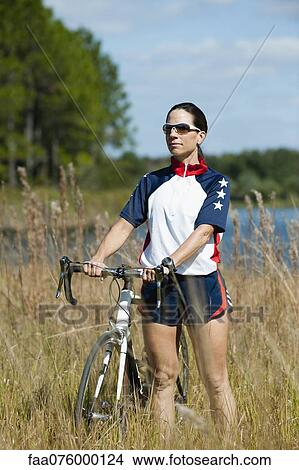 Picture - Woman standing in grass with road bike, portrait. Fotosearch