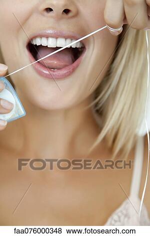 Stock Photo - Woman using dental floss, cropped. Fotosearch