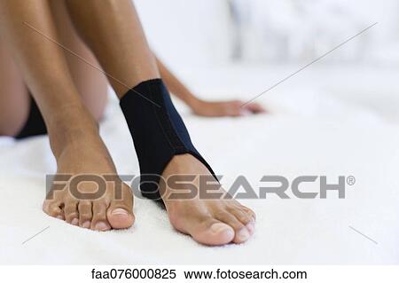 Stock Photography - Woman wearing ankle brace, low section. Fotosearch
