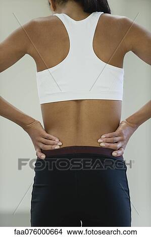 Picture - Woman with backache, rear view. Fotosearch