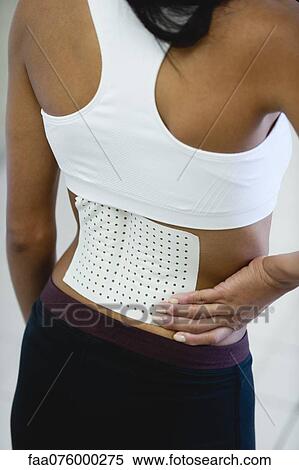 Stock Photography - Woman with bandage on lower back, rear view. Fotosearch
