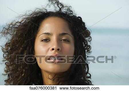 Stock Image - Woman with hair tousled by breeze, portrait. Fotosearch