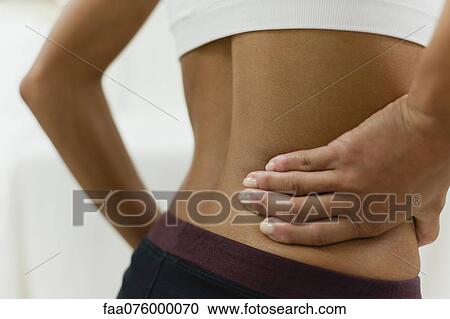 Woman with hand on lower back, mid section View Large Photo Image Stock Image - Woman with hand on lower back, mid section. Fotosearch