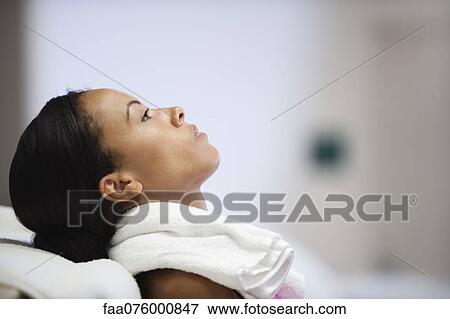 Stock Photo - Woman with towel around neck, side view. Fotosearch