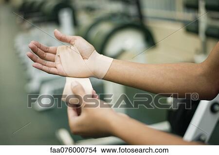 Picture - Woman wrapping hand with bandage, cropped. Fotosearch