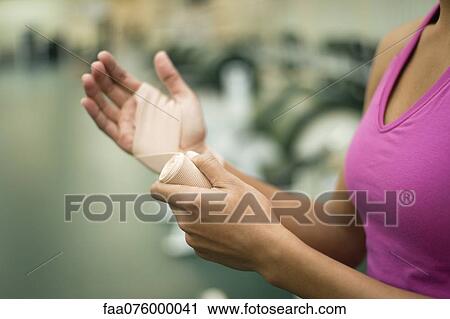 Stock Image - Woman wrapping hand with bandage, cropped. Fotosearch