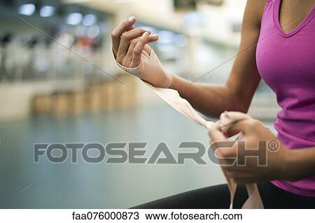 Stock Image - Woman wrapping hand with bandage, cropped. Fotosearch