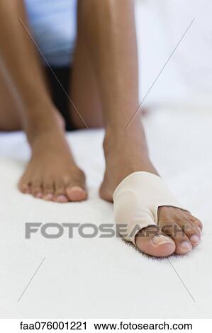 Stock Image - Woman's foot wrapped in brace for injured toe, low section. Fotosearch