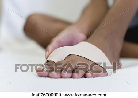 Stock Photo - Woman's foot wrapped in brace for injured toe, low section. Fotosearch