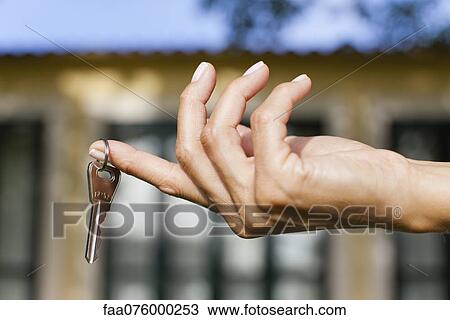 Stock Image - Woman's hand holding key, cropped. Fotosearch