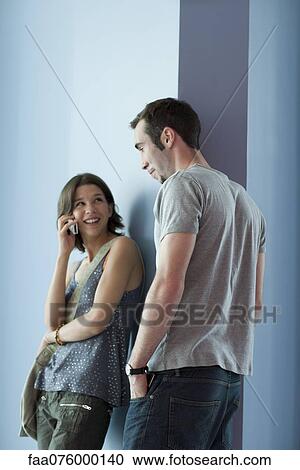 Young adult friends hanging out in hallway, woman talking on cell phone View Large Photo Image Stock Image - Young adult friends hanging out in hallway, woman talking on cell phone. Fotosearch