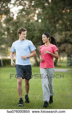 Stock Photography - Young couple jogging on grass. Fotosearch
