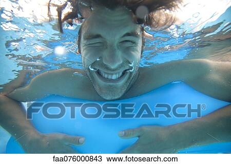 Stock Image - Young man in water, underwater view. Fotosearch