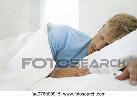 Stock Photography - Young man sleeping in bed. Fotosearch