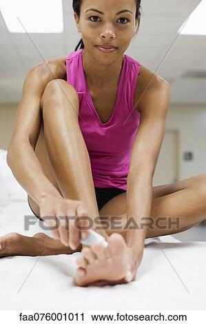 Stock Image - Young woman applying ointment on foot. Fotosearch