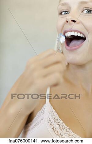 Stock Image - Young woman brushing teeth, cropped. Fotosearch