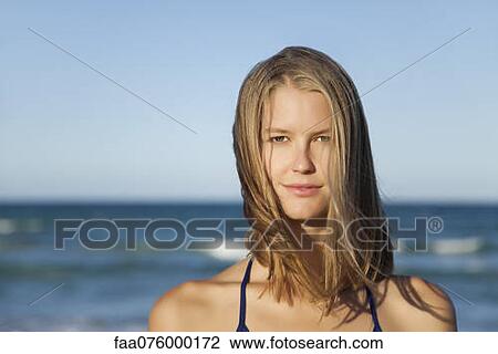 Stock Image - Young woman by ocean, portrait. Fotosearch