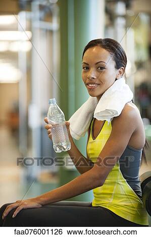 Young woman drinking water after exercising View Large Photo Image Stock Photograph - Young woman drinking water after exercising. Fotosearch