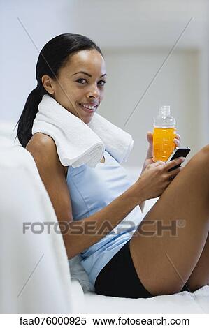 Young woman holding sports drink and cell phone View Large Photo Image Stock Photography - Young woman holding sports drink and cell phone. Fotosearch