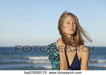 Stock Image - Young woman in bikini by ocean, portrait. Fotosearch