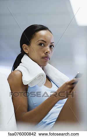 Stock Image - Young woman in sports clothing using cell phone. Fotosearch