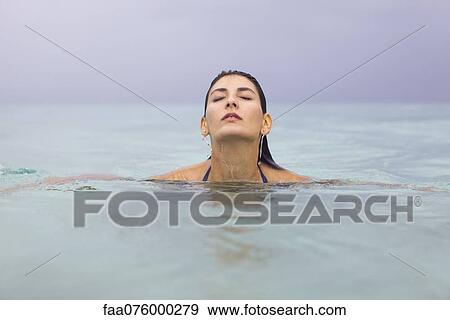 Stock Photo - Young woman in water with eyes closed. Fotosearch