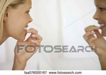 Young woman looking at teeth in mirror, side view View Large Photo Image Stock Photo - Young woman looking at teeth in mirror, side view. Fotosearch