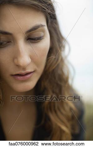Stock Image - Young woman looking down, portrait. Fotosearch