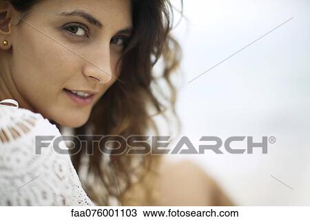 Stock Image - Young woman looking over shoulder, cropped. Fotosearch