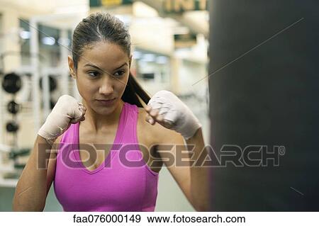 Stock Photo - Young woman punching heavy bag. Fotosearch