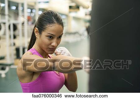 Stock Photograph - Young woman punching heavy bag. Fotosearch