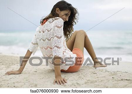 Stock Image - Young woman relaxing on beach. Fotosearch