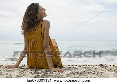 Stock Image - Young woman relaxing on beach. Fotosearch
