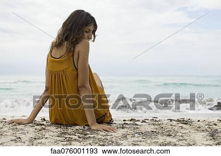 Young woman sitting on beach View Large Photo Image Stock Image - Young woman sitting on beach. Fotosearch